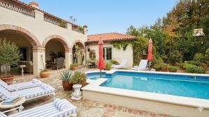 a swimming pool with chairs and umbrellas next to a house at Sandmartins in Suider-Paarl