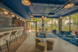 a waiting room with stools and tables and chairs at Hôtel AKENA Serris - Val d'Europe in Serris