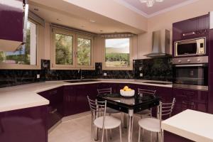 a kitchen with purple cabinets and a black table with chairs at Villa Guesto with Private Pool by MindYourVilla in Anafonítria