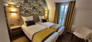 a hotel room with two beds and a window at Hostellerie du Royallieu in Compiègne