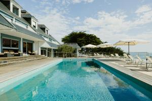 a pool with chairs and umbrellas next to a house at Le Cardinal - Belle-Ile-en-Mer in Sauzon