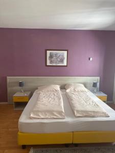 a bed with two white pillows and a purple wall at Hotel Mosel Star in Bernkastel-Kues