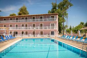 a hotel with a swimming pool with chairs and a building at Apollo Hotel in Laganas