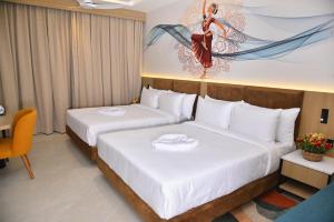 a hotel room with two beds and a painting on the wall at Vels Grand Hotel in Kanchipuram +11 photos