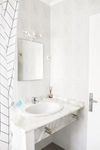 a white bathroom with a sink and a mirror at Malvarrosa Beach Rooms in Valencia