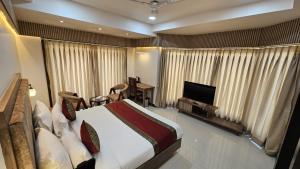a bedroom with a bed and a flat screen tv at Hotel Sainik Grand in Varanasi
