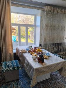 a table with plates of food on it with a window at Geust house Paradise in Arslanbob