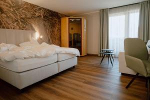 a hotel room with a large bed and a chair at Das Bergfrieden Nature Active Hotel in Martello