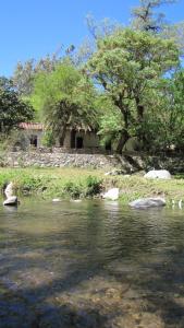 un cuerpo de agua con una casa en el fondo en La Casona del Río en Valle Hermoso