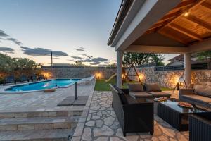 a backyard with a swimming pool and patio furniture at Villa Elder ZadarVillas in Donji Lepuri
