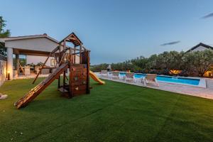 a playground with a slide next to a pool at Villa Elder ZadarVillas in Donji Lepuri