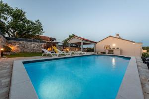 a swimming pool with chairs and a slide at Villa Elder ZadarVillas in Donji Lepuri