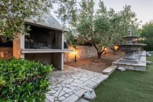 a garden with a fountain in front of a building at Villa Elder ZadarVillas in Donji Lepuri