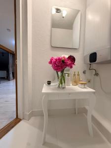a vase of flowers on a white table in a bathroom at Rose & Vintage Mansard in Kuldīga