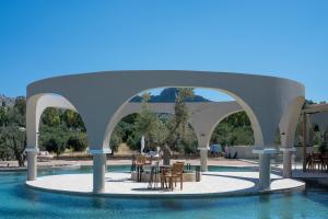 a pavilion with a table and chairs in a pool at The Landmark Villas & Spa in Kolymbia