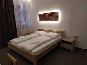 a bed in a bedroom with a picture on the wall at Hotel Maria in Ostrava