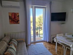 a living room with a couch and a sliding glass door at Family apartments Jimmy - city center in Pag