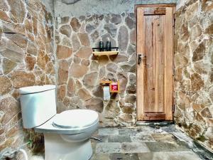 a bathroom with a toilet and a stone wall at Omah Osing Ijen Banyuwangi in Licin