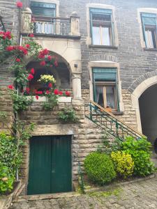 a brick building with a green door and flowers at Bed & Breakfast - Haus Hubertus in Brauneberg