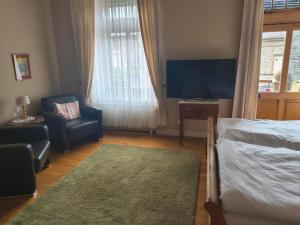 a bedroom with a bed and a chair and a television at Bed & Breakfast - Haus Hubertus in Brauneberg