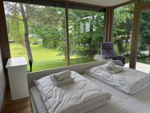 a bedroom with two beds and a large window at Zbilje Lakeside Apartment in Medvode