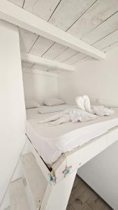 a white bed in a white room with a wooden ceiling at Thea's Bungalow in Costinesti +5 photos