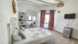 a white bed in a white room with a tv at Thea's Bungalow in Costinesti