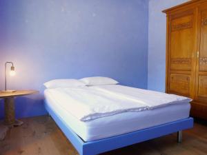 a bed with white sheets and pillows in a blue room at Apartment Casa Malva by Interhome in Malvaglia