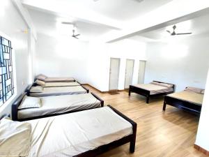three beds in a room with wooden floors at Sekar Inn in Arumuganeri