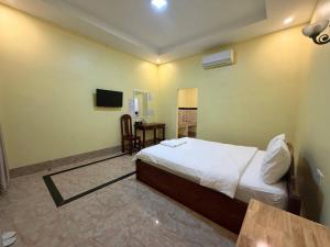 a bedroom with a bed and a table and a television at Mohachey Guesthouse in Phumĭ Bavĕt (2)