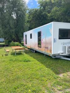 a trailer parked in a field with a picnic table at TinyHouse am Stadthafen in Hennigsdorf