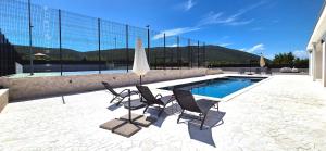 a swimming pool with two chairs and a umbrella at Villa After Set Heaven in Čapljina