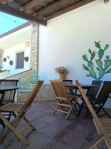 a patio with chairs and a table with a cactus on the wall at Contrada Macchia B&B in Tricase