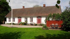 una casa blanca con puertas rojas y una mesa en un patio en Sannagård B&B, en Falkenberg