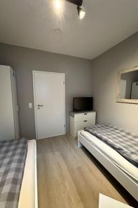 a bedroom with a bed and a door and a television at Apartment FEWO „Am Stausee“ by Interhome in Friesoythe +7 photos