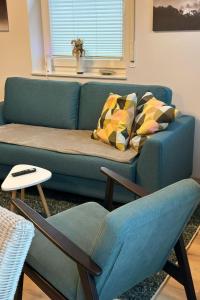 a living room with a blue couch and a chair at Apartment FEWO „Am Stausee“ by Interhome in Friesoythe