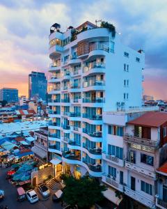a tall white building in a city with a parking lot at Harmony Phnom Penh Hotel in Phnom Penh