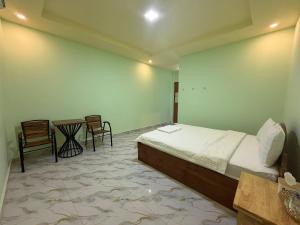 a bedroom with a bed and a table and chairs at Mohachey Guesthouse in Phumĭ Bavĕt (2)
