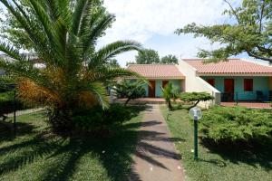 a house with a palm tree next to a sidewalk at Villaggio Le Palatine in Metaponto