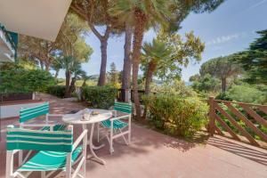 a patio with a table and chairs and palm trees at Hotel Antares in Capoliveri