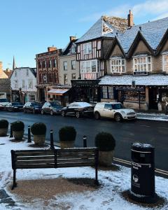 a bench on a city street with parked cars at Cotswold Townhouse - Adults Only in Stow on the Wold