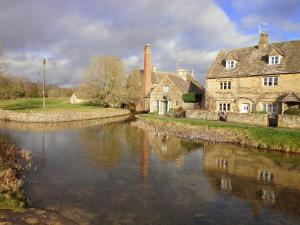an old house and a river in front of a house at Cotswold Townhouse - Adults Only in Stow on the Wold +8 photos