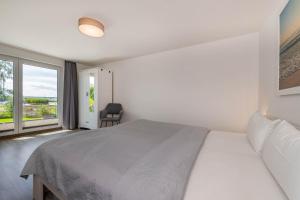 a white bedroom with a bed and a window at Ferienhaus Seebrise in Loddin