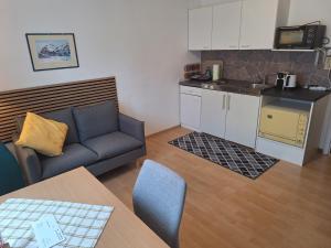 a living room with a couch and a kitchen at Haus Marisa Ferienwohnungen in Aflenz Kurort