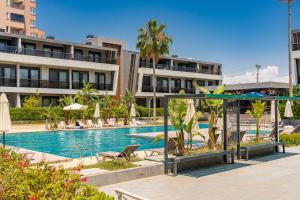 a pool with chairs and umbrellas next to a building at Bliss Residance in Altınkum