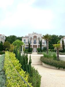 a large white house with a garden in front of it at Olympia Sozopol in Sozopol