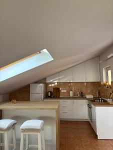 a kitchen with white cabinets and white stools at Family rest apartments in Nikšić +20 photos