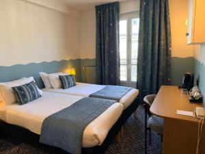 a hotel room with two beds and a desk at Hotel Berne Opera in Paris
