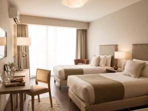 ブエノスアイレスにあるDazzler by Wyndham Poloのベッド2台とデスクが備わるホテルルームです。