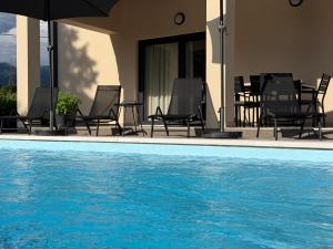 a pool with chairs and an umbrella next to a house at Villa Olealis in Zatka Čepić
